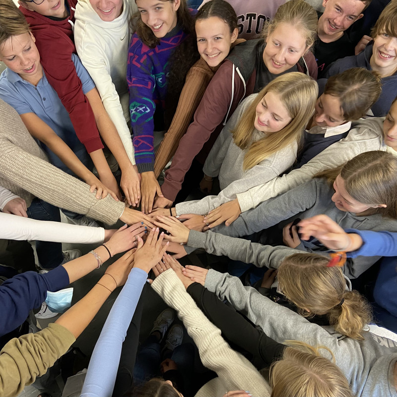 Schulklasse im Kreis mit Händen aneinander