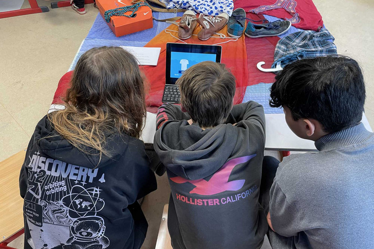 Drei Jugendliche sitzen vor Tablet