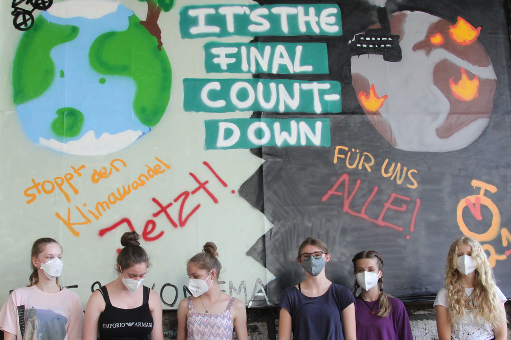 Jugendliche vor Großplakat fordern Klimaschutz